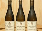 trois bouteilles de vin posées sur un tonneau de vin