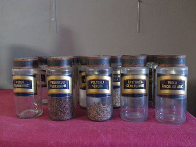 several jars of spices are lined up on a pink table