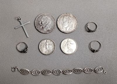 beaucoup de bijoux en argent posés sur une table à côté d'une pièce de monnaie