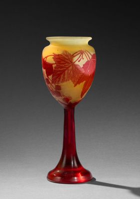 un vase orange et jaune posé sur une table, à côté de l'ombre d'une personne