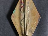 an old brass pin with a pair of scissors on top of it
