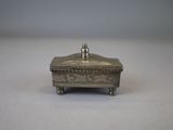 an antique silver box with a lid on a white surface