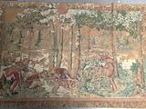 a tapestry hanging on the wall with a picture of a man riding a horse