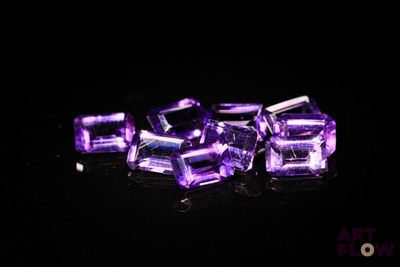 des cubes de cristal violets posés sur une surface noire, avec un fond noir