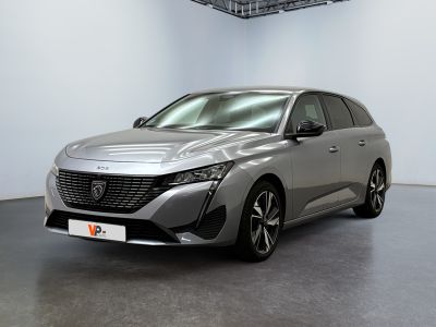 Une voiture argentée est garée dans une grande pièce au sol noir.