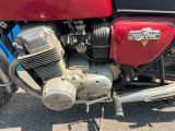 un gros plan d'une moto rouge garée sur un parking