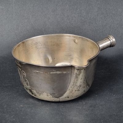 un petit bol en argent avec une anse sur une table