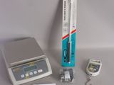 a electronic scale with a pen on it next to other electronic items