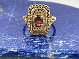 une image d'une bague en or avec une pierre rouge