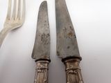 two knives and a fork on a white table