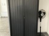 a fan in the corner of a room next to a closet