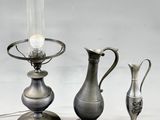 three silver vases and a lamp on a table