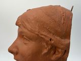 a clay sculpture of a woman ' s head on a table