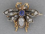 an image of a bee brooch with a blue stone in the middle of it