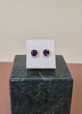 une paire de boucles d'oreilles en améthyste posée sur un bloc de marbre
