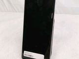 a black cell phone sitting on a stand on a white surface