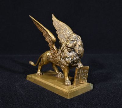 une statue en or représentant un lion ailé portant un panier sur le dos