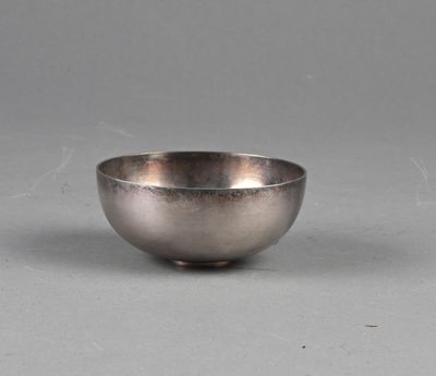 un bol ancien en argent posé sur une surface grise