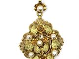 a close up of a gold and pearl pendant on a white background