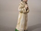 figurine of a monk in a white robe with a green base