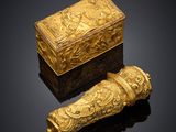 a gold snuff and a box on a black surface