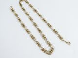 a gold plated necklace with a chain that has been set on a white surface