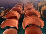 des rangées de chaises orange dans une pièce recouverte d'une moquette verte