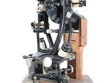 un vieux microscope posé sur un socle en bois, avec un fond blanc