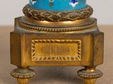 a gold and blue vase on a stand on a table