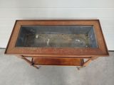 an old wooden table with a glass top sitting on a concrete floor