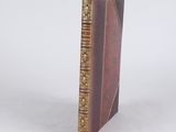 a brown book with gold trim sitting on top of a white surface