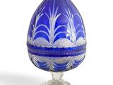 an image of a blue glass egg on a stand on a white background