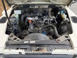 a white car with the hood open and the engine in the trunk