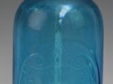 une vieille bouteille en verre bleu avec un bouchon doré et un bec verseur en métal