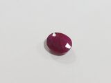 a red ruby stone on a white surface
