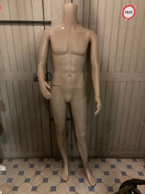 a mannequin in a bathroom with a toilet in the background