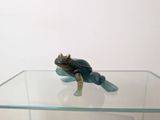 figurine of a frog sitting on top of a glass shelf