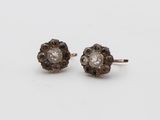 une paire de boucles d'oreilles clous en forme de losange, marron et blanches, posées sur un fond blanc