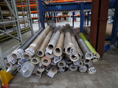 de nombreux rouleaux de métal posés à même le sol dans un entrepôt