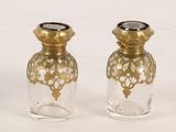 two small glass bottles with gold decorations on them