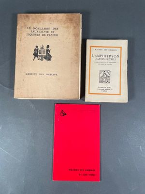 Trois livres sont posés sur une table ; l'un d'entre eux a une couverture rouge.