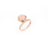 un gros plan d'une bague en pierre rose sur fond blanc
