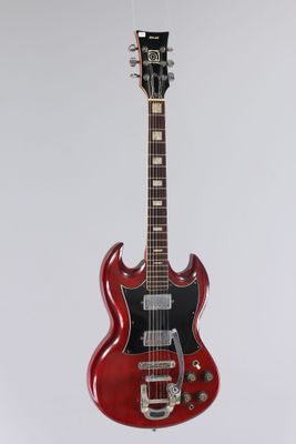 an electric guitar hanging from a rope on a white wall