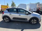 La petite voiture est garée sur le parking, à côté d'autres véhicules.