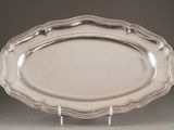 an oval silver platter on a stand on a grey background