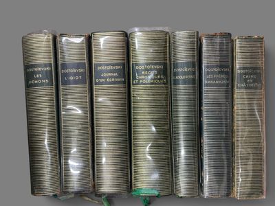 several old books are lined up on a shelf in a row