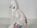 a white cat sitting on a plate with flowers on it