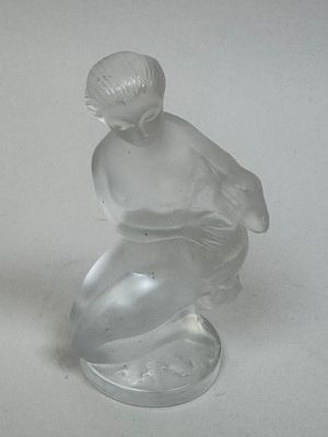 a glass figurine of a boy sitting on top of a table
