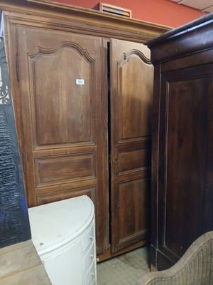 a wooden armoire next to a toilet in a room