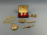 a gold necklace, watch, pen, and other items on a table